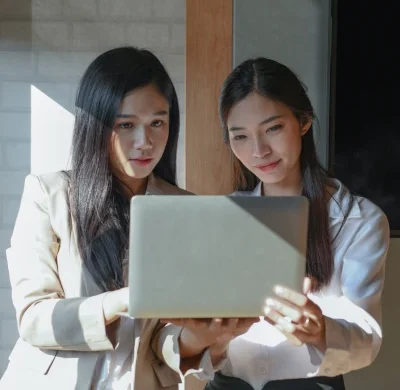 two-female-employees-are-using-laptop-she-stand-at-2024-12-06-08-11-21-utc